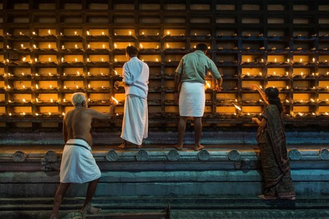 Oil lamps being lit in niches on the outer wall of the temple for the Hindu fire ceremony Aarti