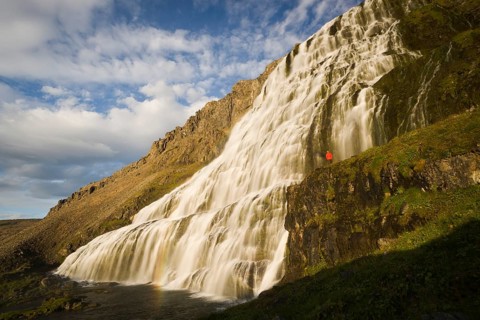 Person standing in front of the Dynjandi waterfall