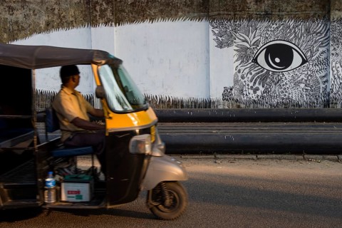 Rickshaw driver looking at graffiti on a wall in Kochi