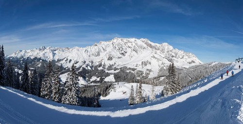 Skiers on ski slope in front of mountain scenery