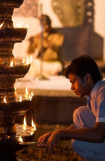 Young man lighting oil-soaked wicks on a stone chandelier