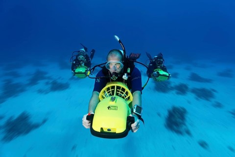 Divers with diver propulsion vehicles exploring a coral reef