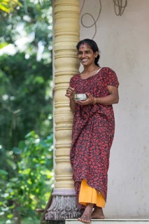 Smiling woman leaning against a pillar in Alappuzha