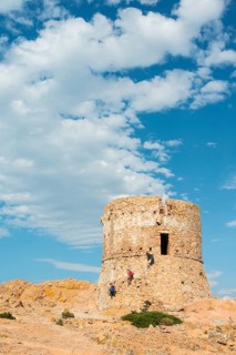 Three people walking down from a Genoese tower