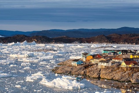 Colourful timber houses by the sea with iceberg fragments