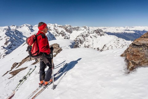 Ski tourer on the summit ridge with overhanging snow
