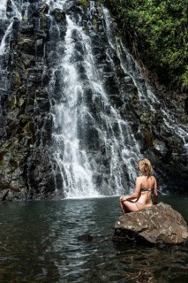Woman sitting in front of the Kepirohi waterfall