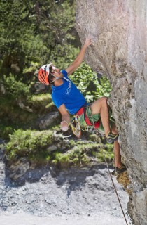 Sport climber wearing a helmet climbing a rock face