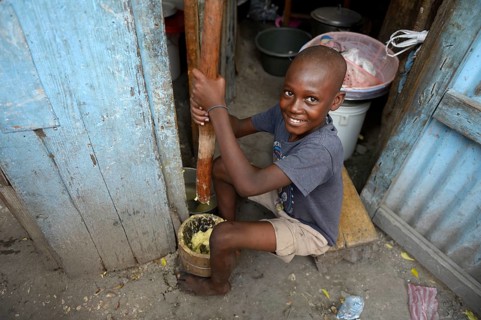 Boy pounding corn into flour in a mortar