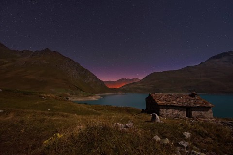Night sky above Mont Cenis lake and a hut
