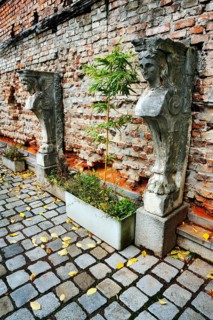 Stone sculptures and bamboo in front of a brick wall