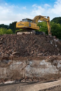 Excavator standing on a large rubble heap
