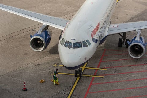 Worker attaching brake pads to a parked aircraft
