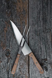 Carving knife and fork on a rustic wooden boards