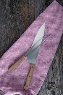 Carving knife and fork with a kitchen towel on rustic wooden boards