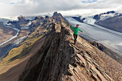 Mountaineer on the summit ridge in front of a glacier tongue