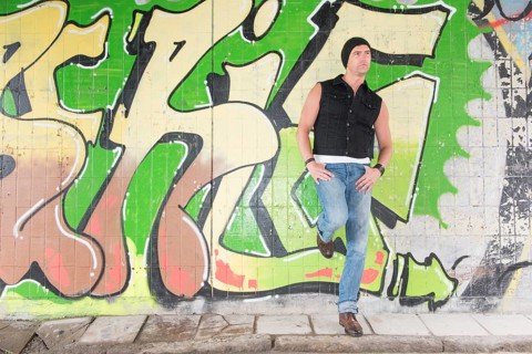 Portrait of a man standing in front of wall covered with graffiti