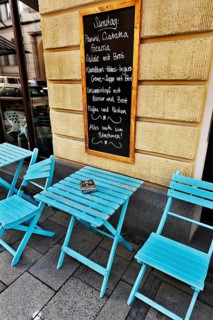 Street cafe with a menu board and blue tables and chairs