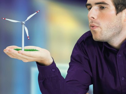 Man blowing a miniature wind turbine in his hand