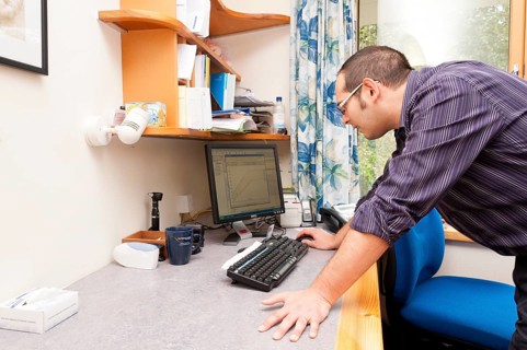 GP doctor using a computer in his surgery