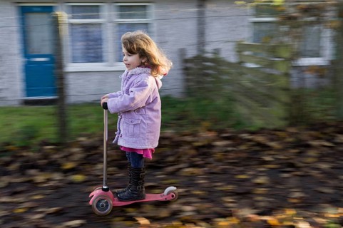 Four-year-old girl having fun riding a scooter