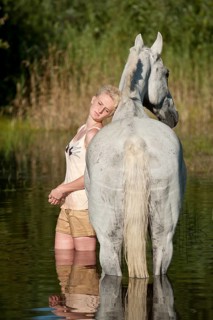 Woman standing in water with a Hanoverian horse