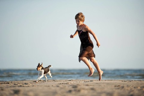 Girl running with a Dansk-Svensk Gardshund or Danish-Swedish Farmdog on the beach