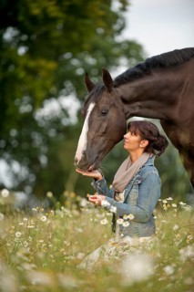 Woman beside a Hanoverian horse in a meadow