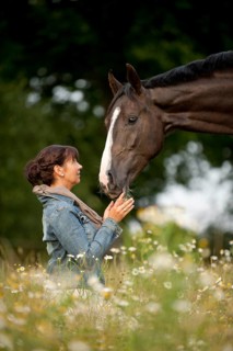 Woman with a Hanoverian horse in a meadow