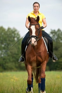 Woman riding a galloping Hanoverian horse in a meadow