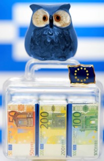 Owl on a suitcase full of money in front of a Greek flag
