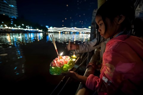 Young girl placing a ceremonial raft in the river