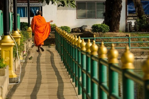 Buddhist monk walking across a bridge