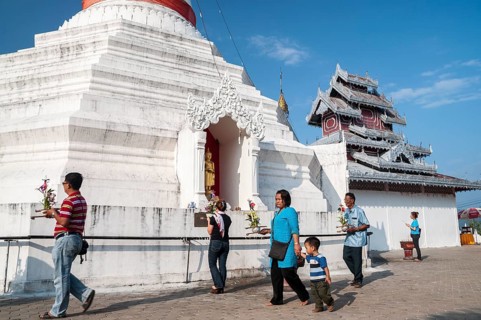 People with offerings walking around a Pagoda or Chedi