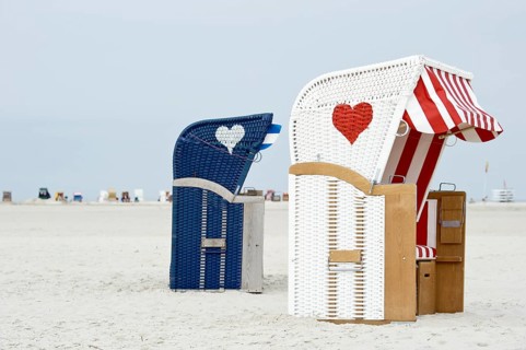 Roofed wicker beach chairs with hearts on the beach at Norddorf