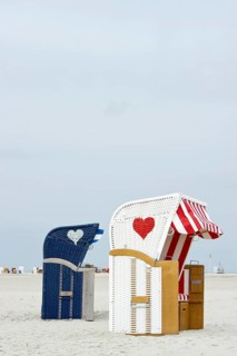 Roofed wicker beach chairs with hearts on the beach at Norddorf
