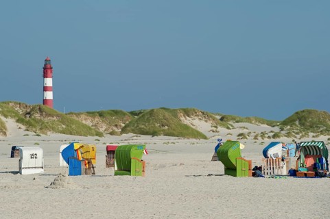 Roofed wicker beach chairs and lighthouse at Nebel