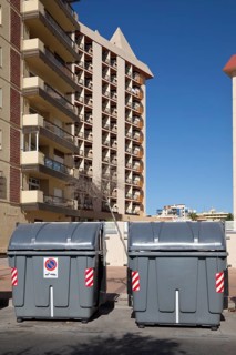 Wheeled trash cans standing in front of an apartment complex