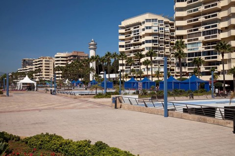 Beach promenade with high-rise buildings and a lighthouse
