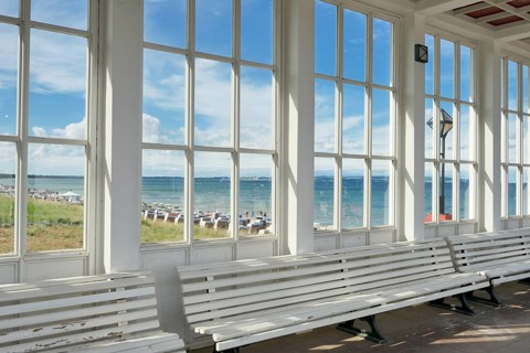 Looking through the window of the pavilion of the Kurhaus spa building towards the Baltic Sea and the beach