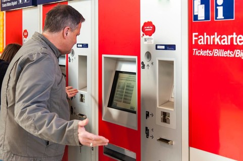Confused man standing in front of a ticket machine