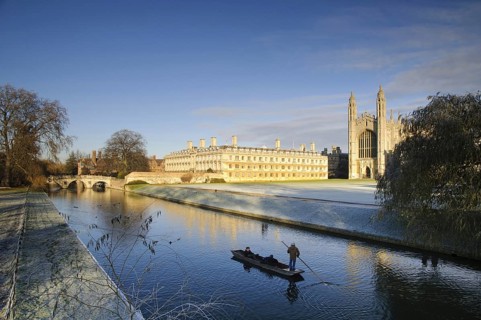 View of river with punt approaching bridge and college buildings in frost
