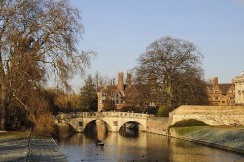 View of river with punt approaching bridge and college buildings in frost