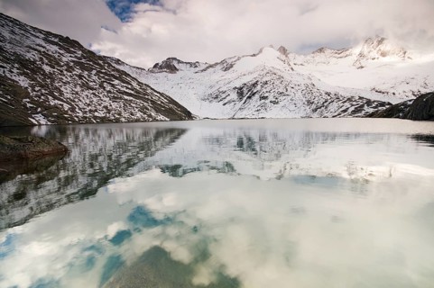 Foggy atmosphere at Unterer Gerlossee lake with mountains Wildgerlosspitze