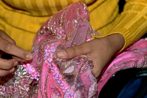 Tailor embroidering a party dress with glittering sequins