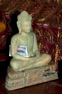Buddha statue made of marble with a banknote as an offering inside the pagoda of the Buddhist temple of Wat Phnom