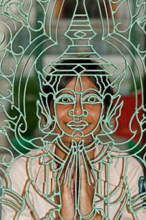 Young Khmer woman looking through a metal lattice gate with a Buddha figure
