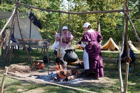 Women with a cooking pot over a campfire