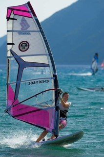 Female windsurfer surfing across the water on her board