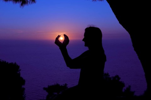 Silhouette of a woman against the sunset sky
